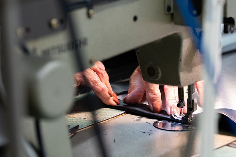 A Rifkin machinist stitching leather trim on an industrial sewing machine at the Hanover Township factory